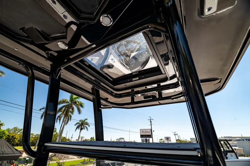 Slide: The Image of 2024 Crevalle 26 HCO boat T-top view with clear sky and palm trees. - 38
