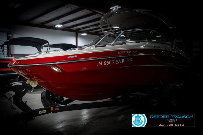 Slide: The Image of 2014 Yamaha Boats 242 Limited S in a showroom, red hull, on a trailer. - 4