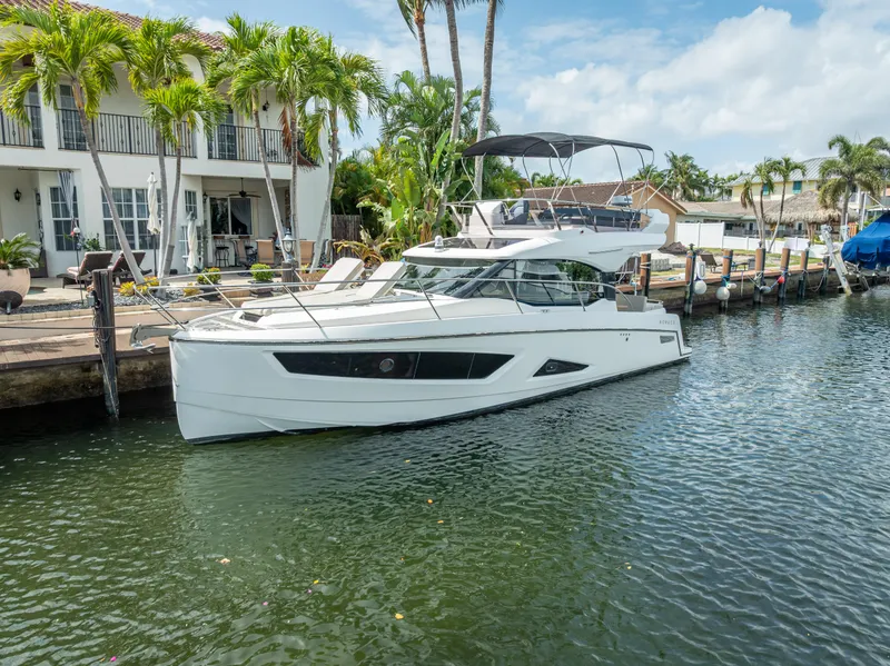Slide: The Image of Luxury Skamander Monaco 2021 yacht docked by waterfront home with palm trees. - 2
