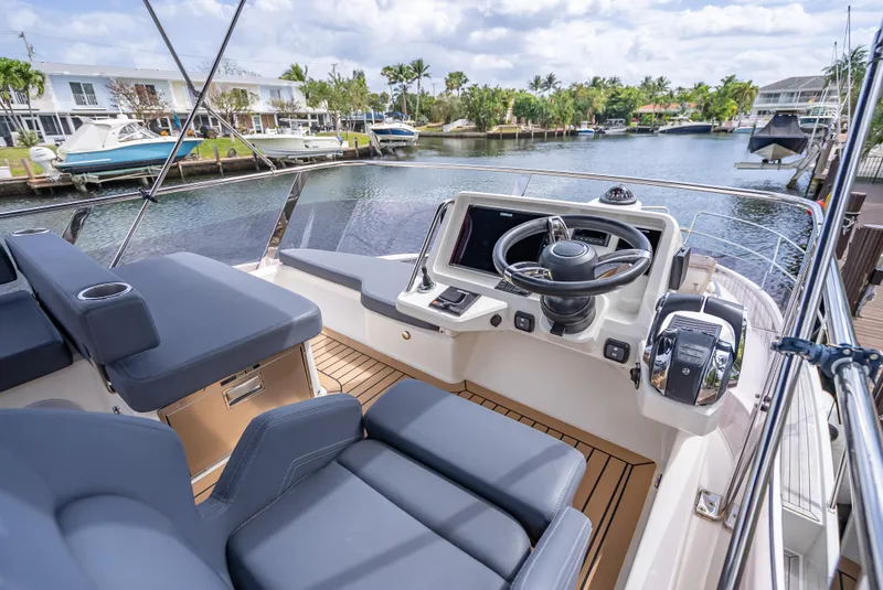 Slide: The Image of 2021 Skamander Monaco yacht cockpit with modern controls, luxurious seating, and scenic marina view. - 32