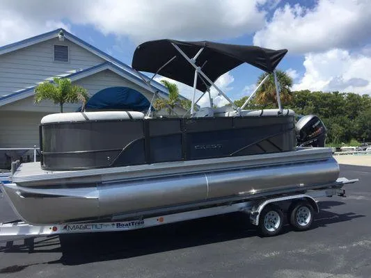 Slide: The Image of 2024 Crest LX 200 SLC pontoon boat on trailer, parked outdoors under a blue sky. - 2