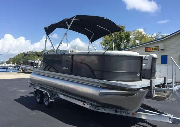 Slide: The Image of 2024 Crest LX 200 SLC pontoon boat on trailer, parked outdoors under blue sky. - 5