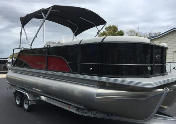 Slide: The Image of 2024 Crest Classic LX 220 SLSC pontoon boat on trailer, parked outdoors. - 3