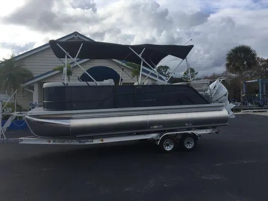 Slide: The Image of 2024 Crest LX 220 SLRC pontoon boat with canopy, parked on a trailer. - 4