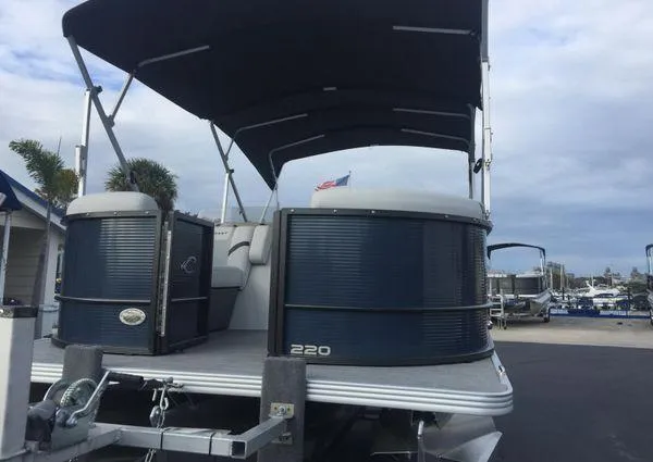 Slide: The Image of 2024 Crest LX 220 SLRC pontoon boat with canopy and outboard motor, parked outdoors. - 6