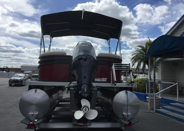 Slide: The Image of 2024 Crest LX 220 SLC pontoon boat with outboard motor, parked under cloudy sky. - 2