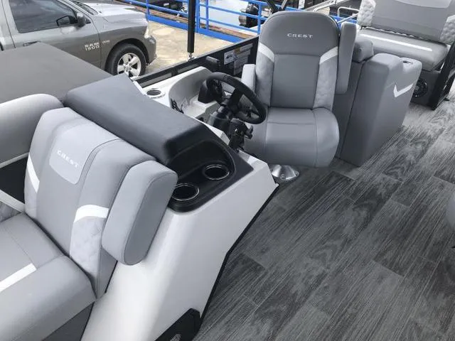 Slide: The Image of 2025 Crest Classic LX 220 SLRC pontoon boat, sleek design, docked on a trailer. - 6
