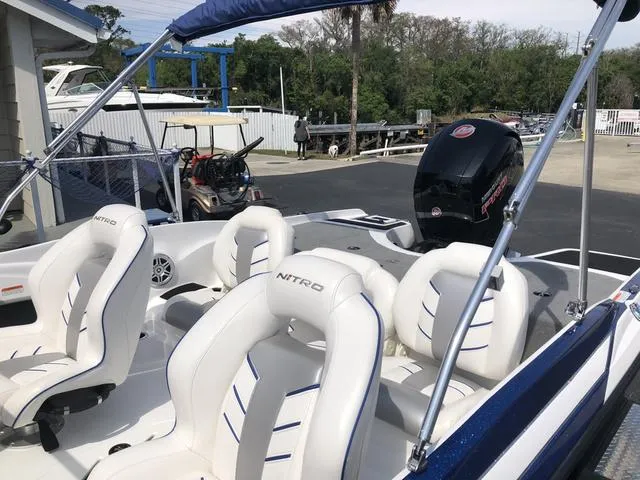 Slide: The Image of 2021 Nitro Z19 Sport boat with white seating and outboard motor in a marina setting. - 17