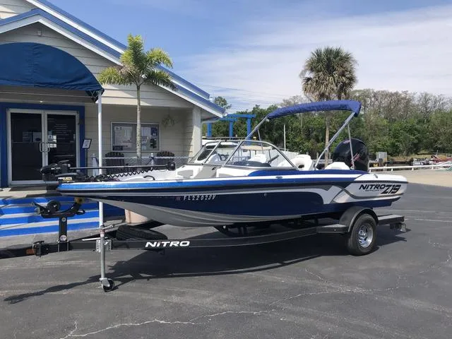 Slide: The Image of 2021 Nitro Z19 Sport boat on trailer, parked outside a building with palm trees. - 2