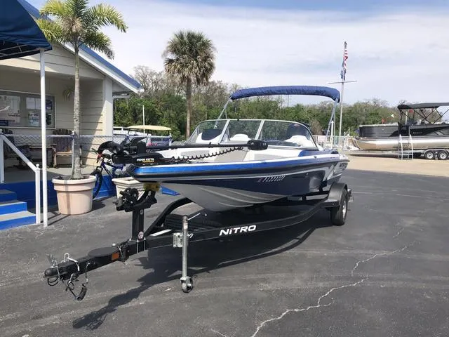 Slide: The Image of 2021 Nitro Z19 Sport boat on trailer, parked near palm trees and a building. - 3