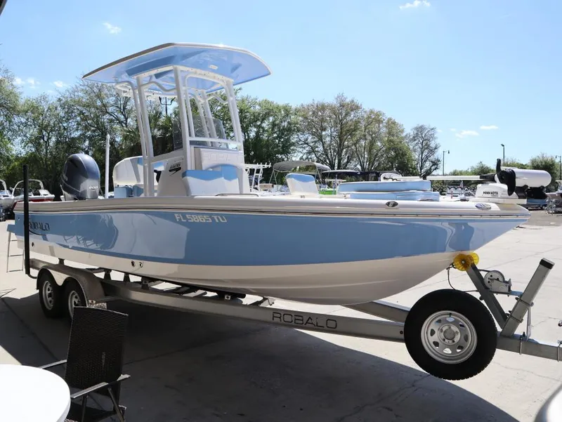 Slide: The Image of 2023 Robalo 226 Cayman boat on trailer, light blue hull, parked outdoors. - 5