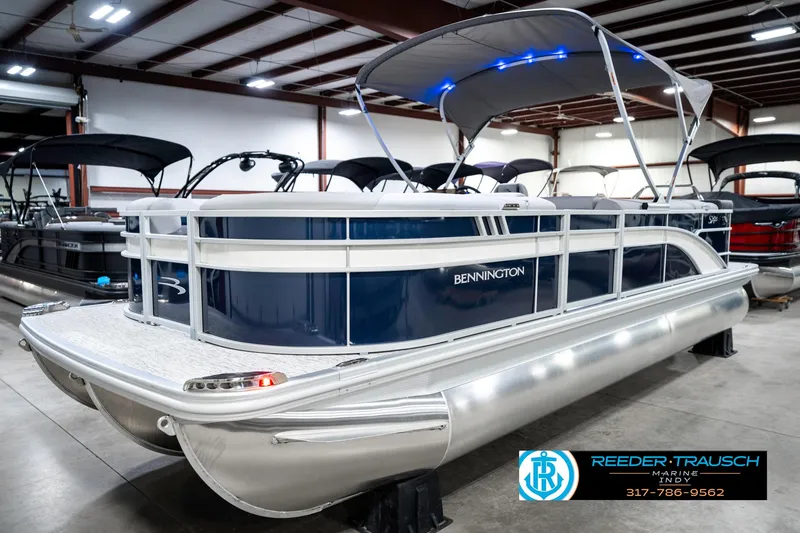 Slide: The Image of 2025 Bennington 23 S Cruise pontoon boat in showroom with canopy and blue accents. - 3