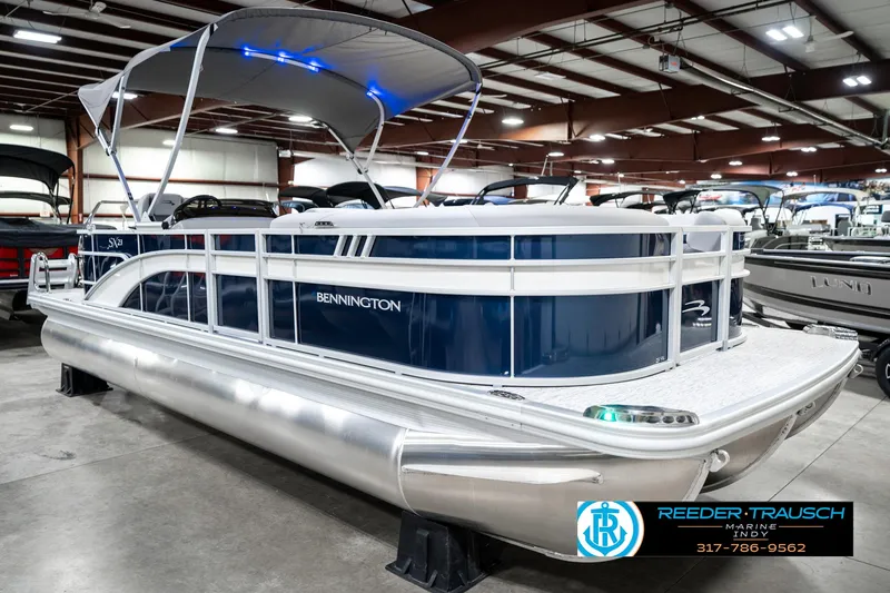 Slide: The Image of 2025 Bennington 23 S Cruise pontoon boat in showroom with canopy and blue accents. - 6