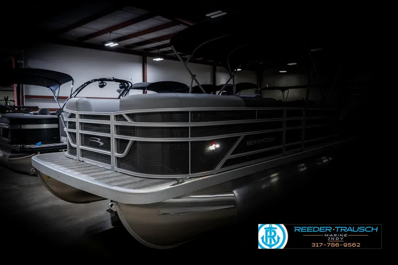 Slide: The Image of 2025 Bennington 21 SS pontoon boat in a dimly lit showroom. - 4