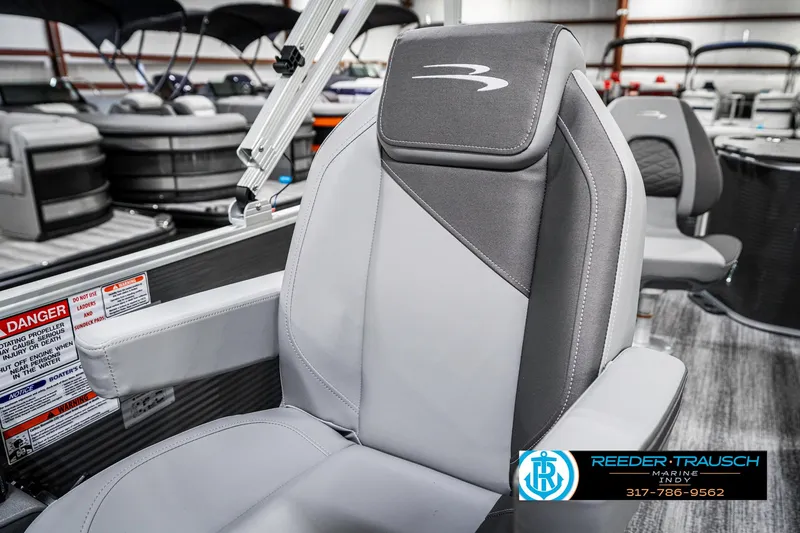 Slide: The Image of 2025 Bennington 21 SS boat seat with gray upholstery and logo, displayed in a showroom. - 43