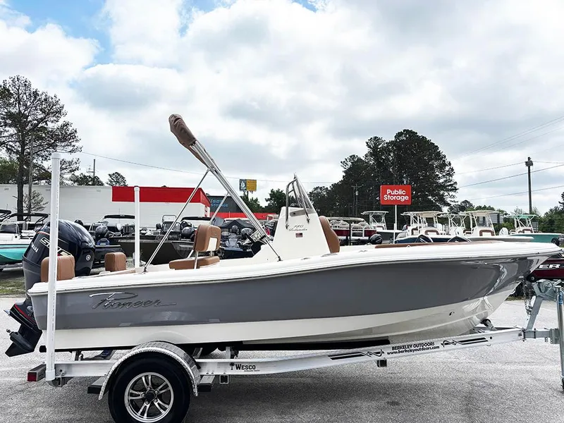 Slide: The Image of 2025 Pioneer 180 Islander boat on trailer, parked outdoors, with trees and storage facility in background. - 5