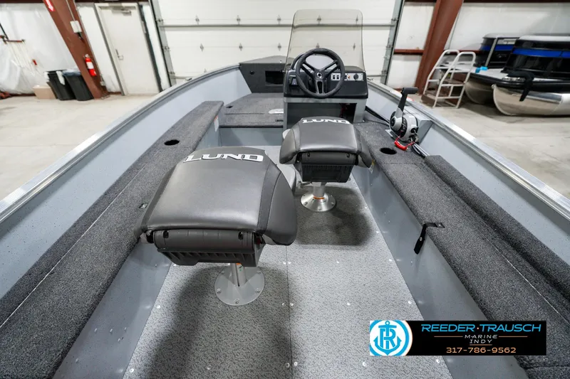 Slide: The Image of 2025 Lund 1600 Fury boat interior with seating and steering wheel in a garage setting. - 14