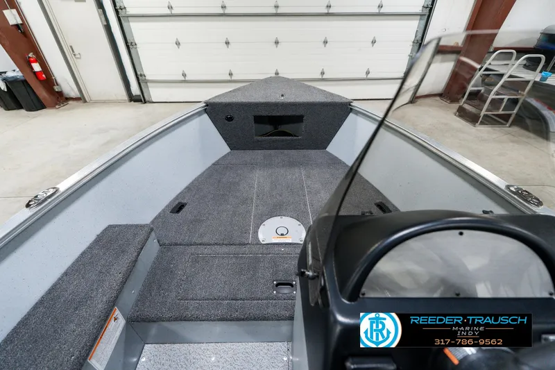 Slide: The Image of 2025 Lund 1600 Fury boat interior with gray carpet and steering console in a garage. - 15