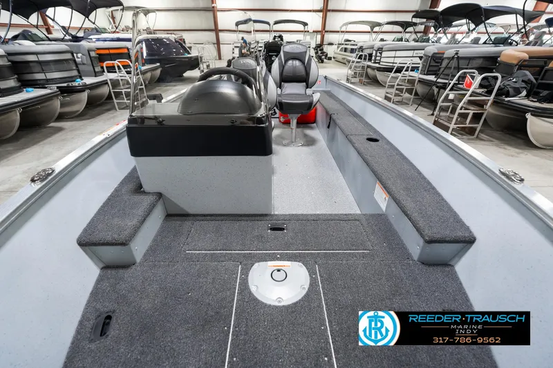Slide: The Image of 2025 Lund 1600 Fury boat interior in showroom, featuring seating and storage compartments. - 16