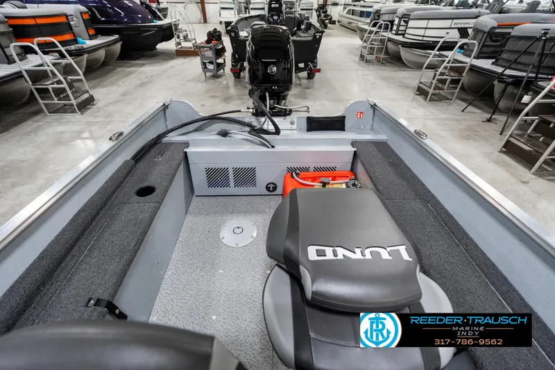 Slide: The Image of 2025 Lund 1600 Fury boat interior with seating and motor, displayed in a showroom. - 17