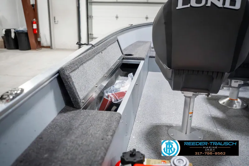 Slide: The Image of 2025 Lund 1600 Fury boat interior with storage compartment and seating in a garage setting. - 25