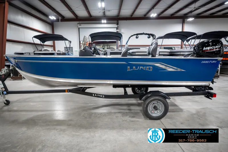 Slide: The Image of 2025 Lund 1600 Fury boat in blue, displayed indoors on a trailer. - 9