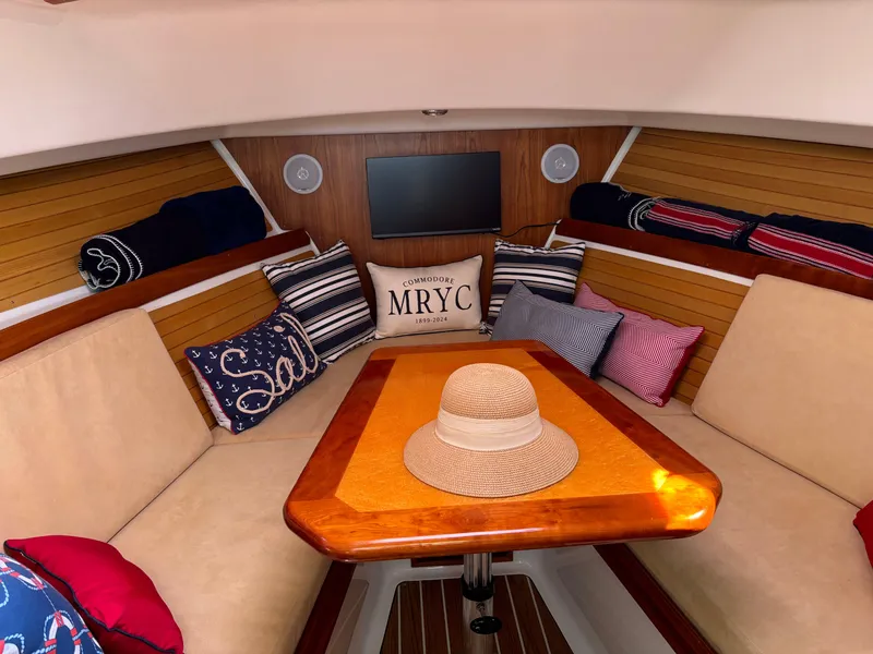 Slide: The Image of Cozy interior of 2007 Back Cove 29 boat with cushions and a straw hat on the table. - 12