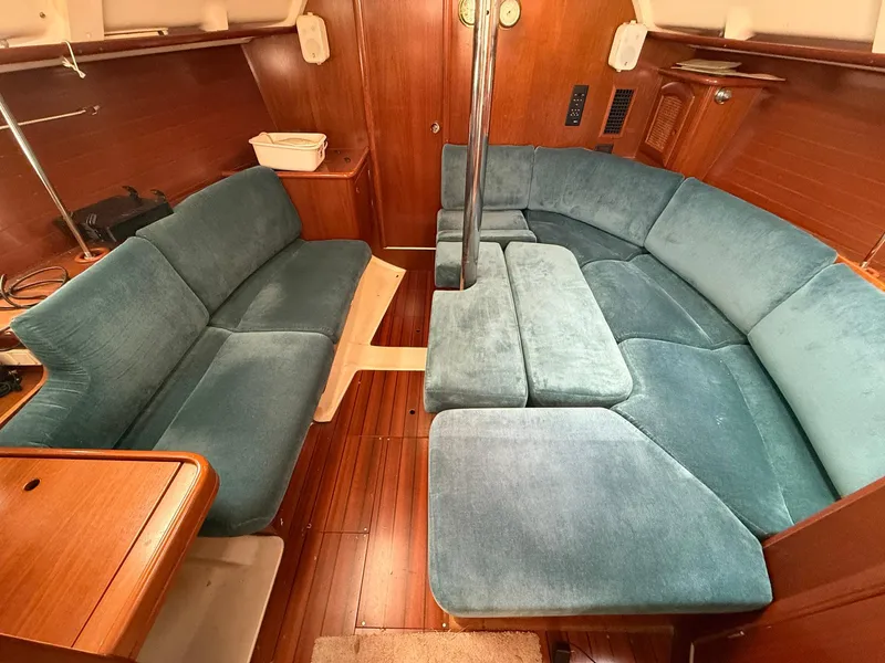 Slide: The Image of Interior of 1998 Beneteau Oceanis 352 sailboat with blue cushioned seating and wooden flooring. - 12