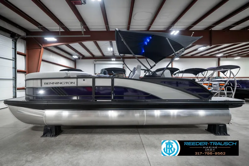 Slide: The Image of 2025 Bennington 22 MSB pontoon boat in showroom, featuring sleek design and canopy. - 10