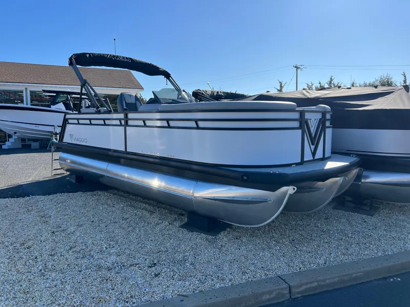 The Image of 2025 Viaggio Lago V20U pontoon boat displayed outdoors on gravel. - 0