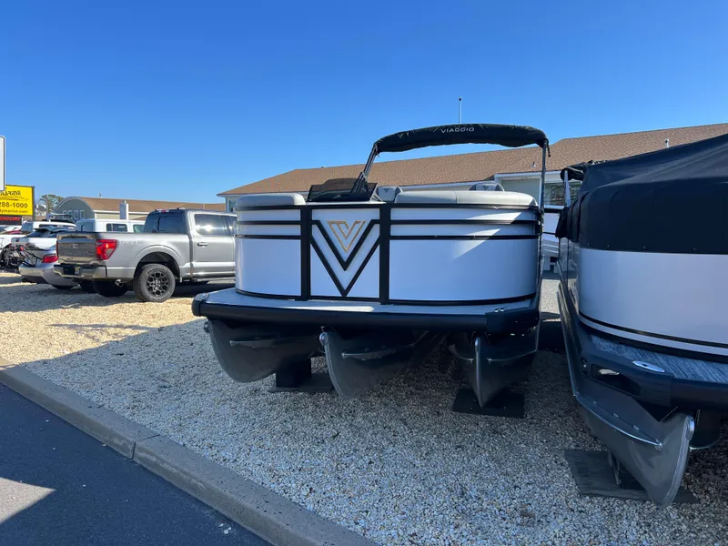 Slide: The Image of 2025 Viaggio Lago V20U pontoon boat displayed outdoors on gravel lot. - 1