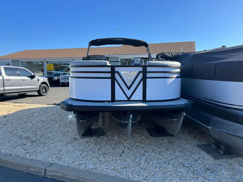 Slide: The Image of 2025 Viaggio Lago V20U pontoon boat displayed outdoors on gravel. - 2