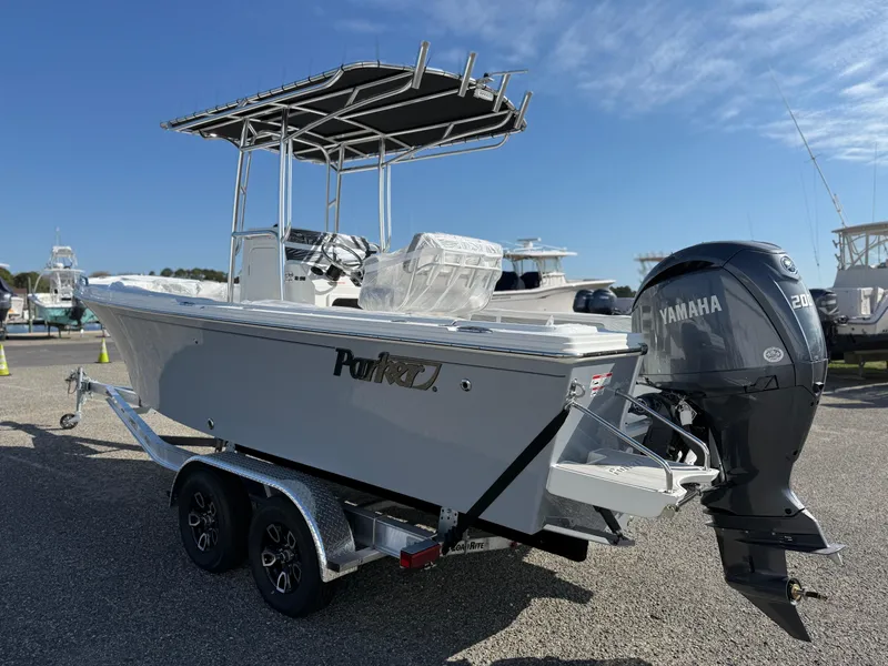 Slide: The Image of 2025 Parker 21SE boat with Yamaha engine on a trailer, parked outdoors under a clear sky. - 1