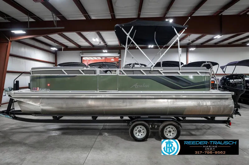 Slide: The Image of 2023 Avalon 2380 VLS pontoon boat in showroom, featuring green and silver design. - 11