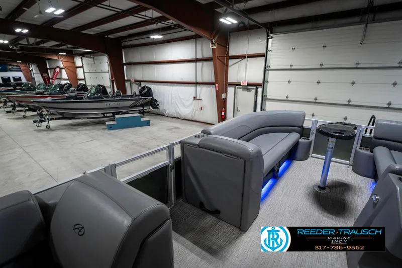 Slide: The Image of 2023 Avalon 2380 VLS pontoon boat interior in showroom with seating and blue lighting. - 29