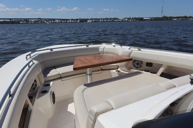 Slide: The Image of 2023 Boston Whaler 350 Realm boat interior with seating and table on the water. - 13