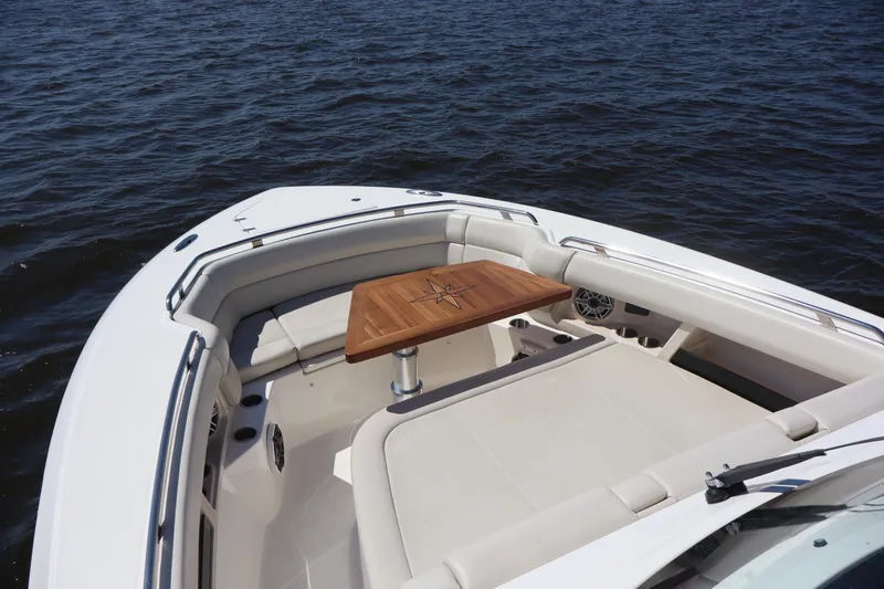 Slide: The Image of 2023 Boston Whaler 350 Realm boat interior with wooden table on calm water. - 17
