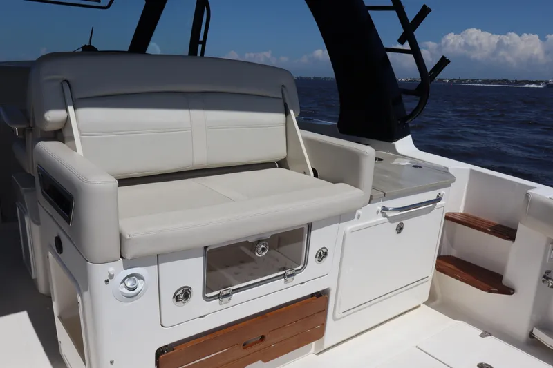 Slide: The Image of 2023 Boston Whaler 350 Realm interior with seating and storage, ocean view in background. - 18