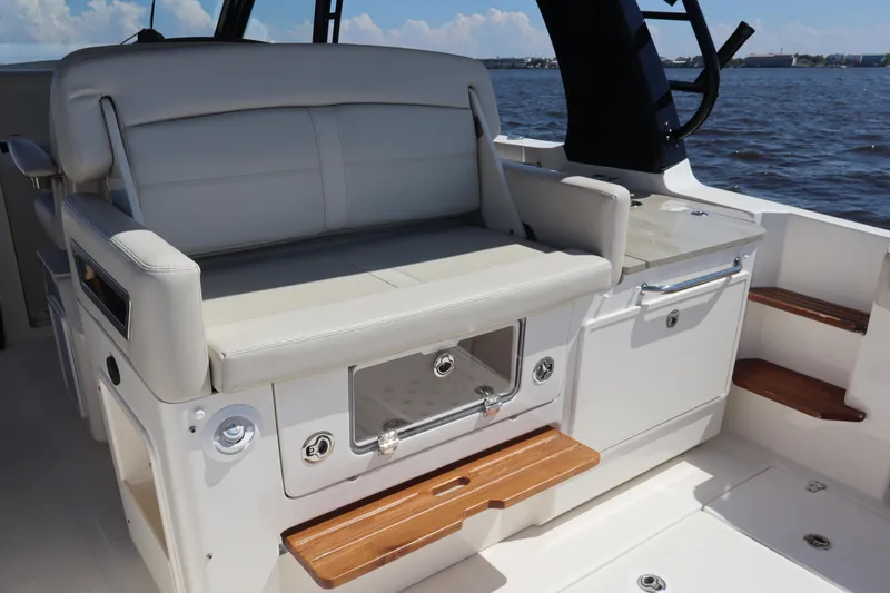 Slide: The Image of 2023 Boston Whaler 350 Realm interior with cushioned seating and storage, overlooking the water. - 19