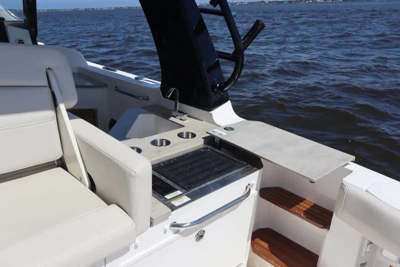 Slide: The Image of 2023 Boston Whaler 350 Realm boat interior with seating and grill, on open water. - 21