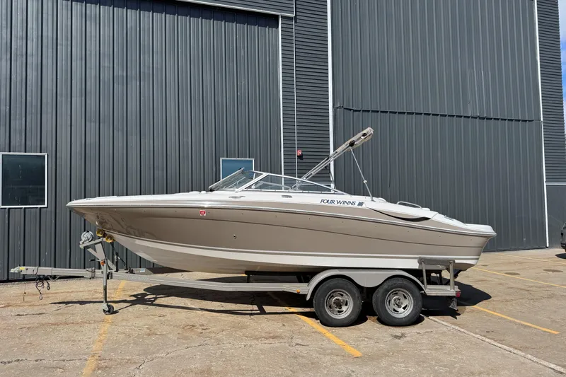 Slide: The Image of 2004 Four Winns 210 Horizon boat on trailer, parked outside a large building. - 0