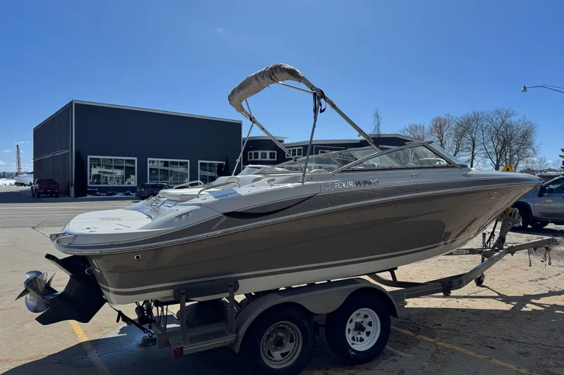 Slide: The Image of 2004 Four Winns 210 Horizon boat on trailer, parked outdoors under clear blue sky. - 2