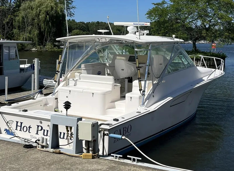Slide: The Image of 2006 Cabo 40 Express boat docked by a serene lake. - 2