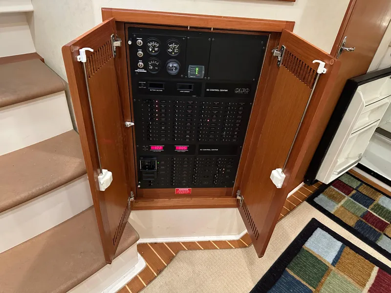 Slide: The Image of Electrical panel inside a 2006 Cabo 40 Express boat, with open wooden cabinet doors. - 30
