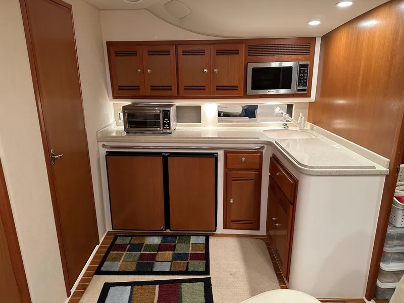Slide: The Image of 2006 Cabo 40 Express yacht kitchen with wood cabinets, microwave, and compact appliances. - 31