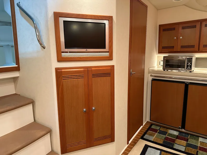 Slide: The Image of Interior of 2006 Cabo 40 Express yacht with TV, cabinets, and kitchenette. - 32