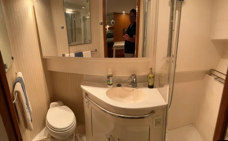 Slide: The Image of Bathroom interior of a 2006 Cabo 40 Express yacht, featuring a sink, toilet, and shower. - 34