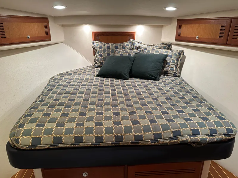 Slide: The Image of Cabo 40 Express 2006 cabin with patterned bedding and pillows, featuring wooden storage cabinets. - 36