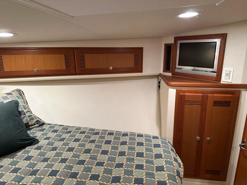Slide: The Image of Interior of 2006 Cabo 40 Express yacht with bed, TV, and wooden cabinets. - 37