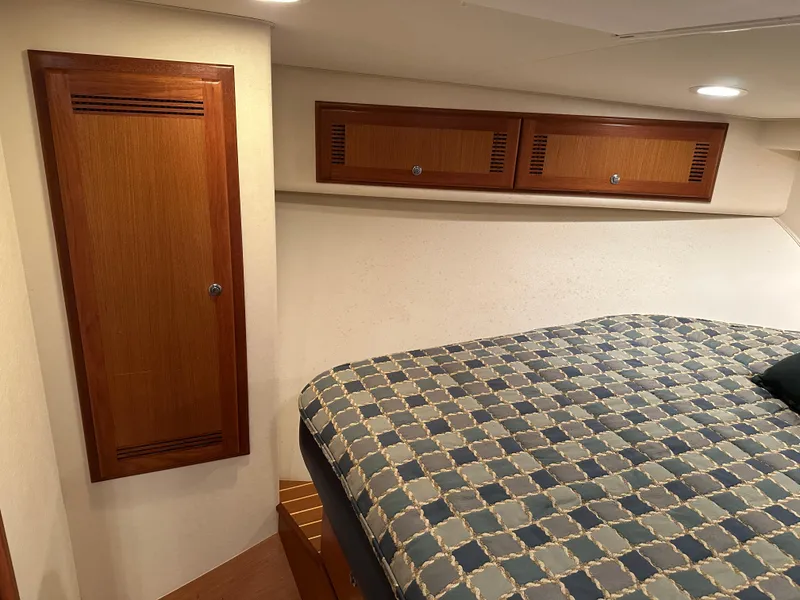 Slide: The Image of 2006 Cabo 40 Express cabin interior with bed, wooden cabinets, and soft lighting. - 38